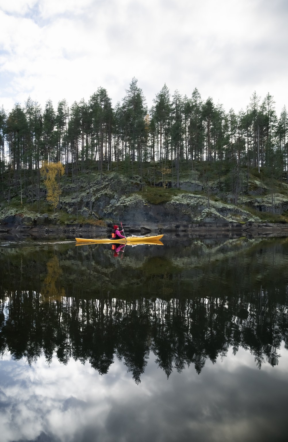 Kayaker on calm lake in Kolovesi between cliffs
